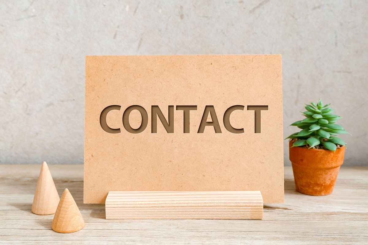 木製プレートに“CONTACT”の文字が彫られた、お問い合わせを表すイメージ画像。小さな観葉植物と木製オブジェ付き
